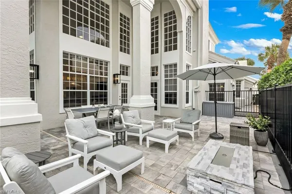 a view of a patio with a dining table and chairs under an umbrella with a barbeque grill