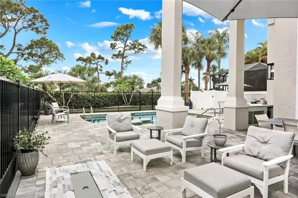 a view of a patio with couches table and chairs under an umbrella with a potted plant