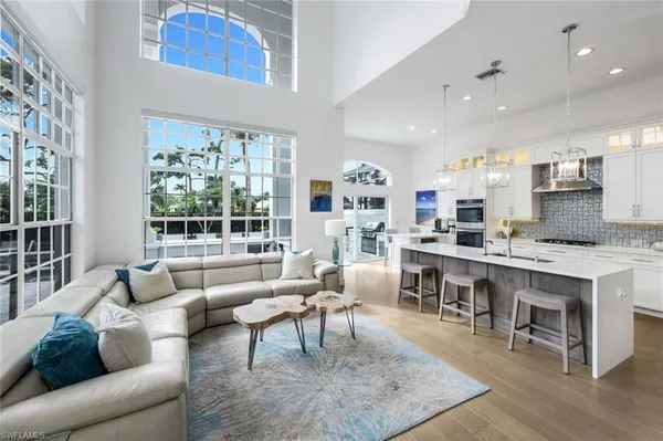 a living room with stainless steel appliances granite countertop furniture a rug kitchen view and a window