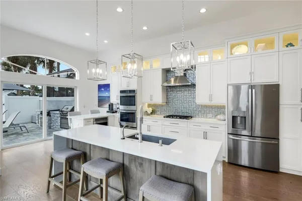 a kitchen with stainless steel appliances a refrigerator a stove a sink and a dining table with wooden floor