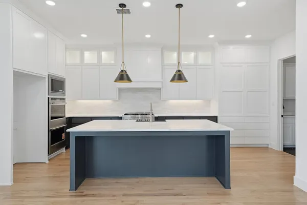 a large kitchen with a stove a sink dishwasher and a refrigerator with wooden floor