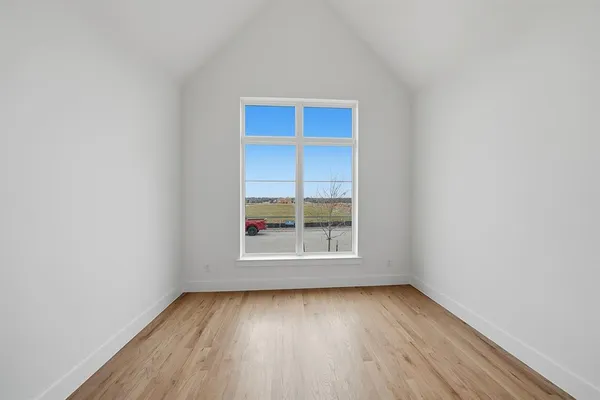 a view of an empty room with a window and kitchen view