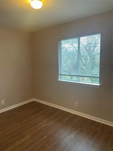 a view of a big room with wooden floor and windows