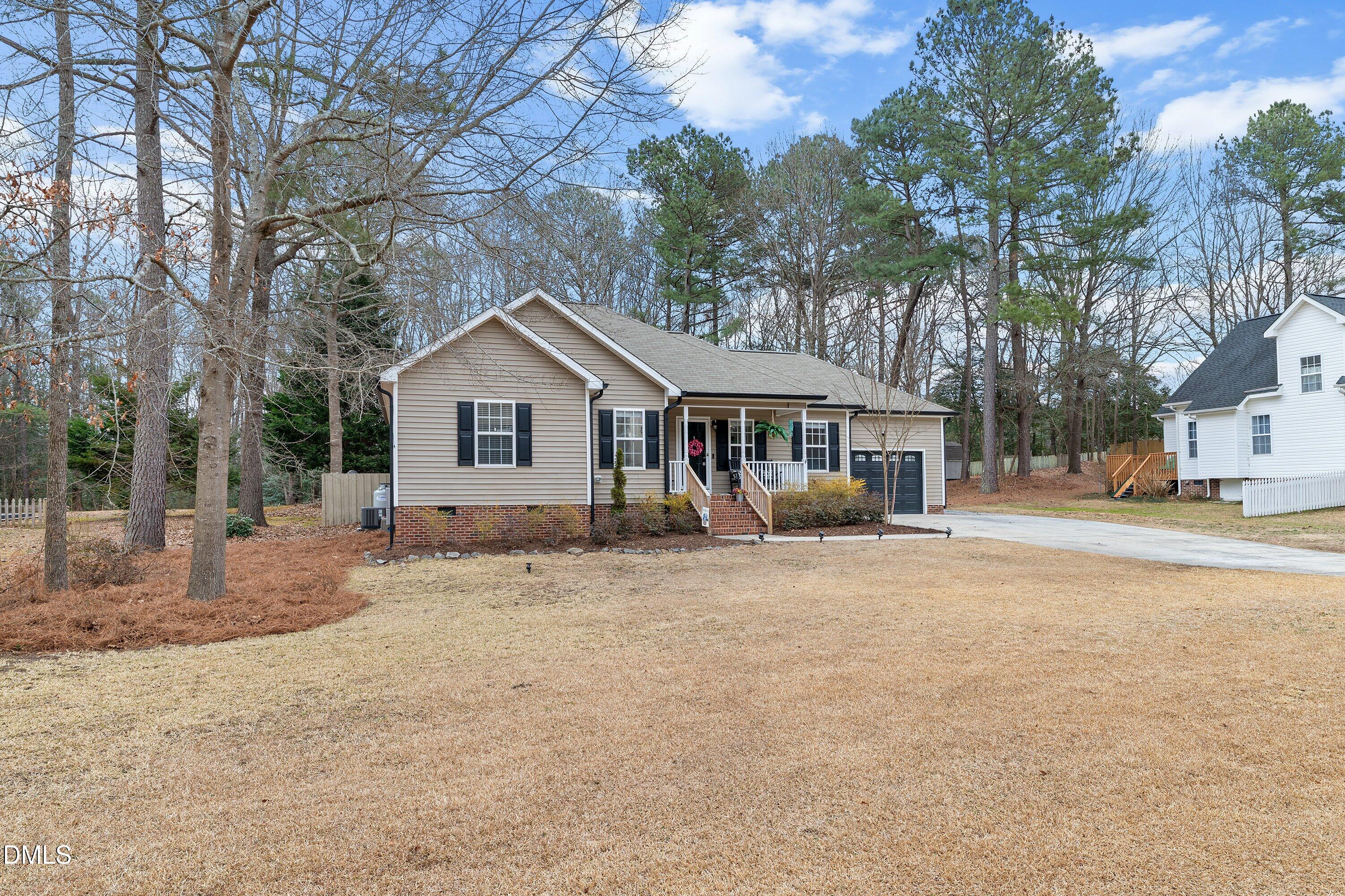 234 Linville Lane Willow Spring, NC 27592 - Photo 2 of 34 a front view of a house with a dirt yard and large trees