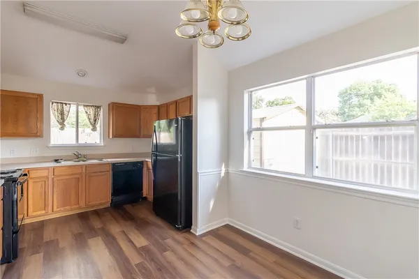 a kitchen with stainless steel appliances granite countertop a refrigerator a sink dishwasher a stove and white countertops with wooden floor