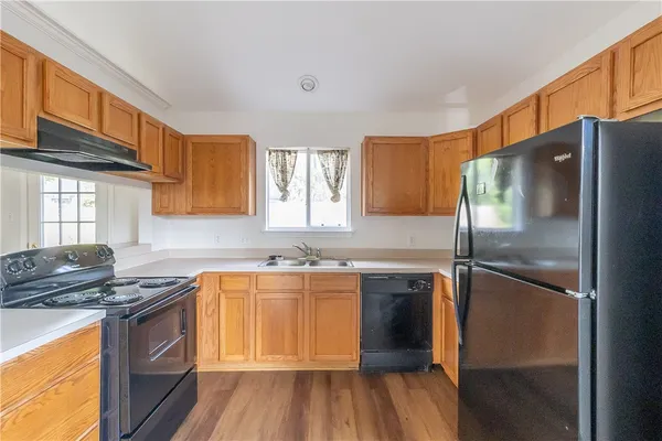 a kitchen with stainless steel appliances granite countertop a refrigerator a sink dishwasher a stove and white countertops with wooden floor