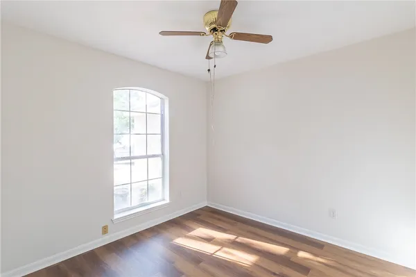 an empty room with windows and fan