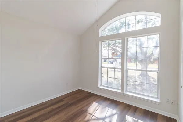 an empty room with wooden floor chandelier and windows