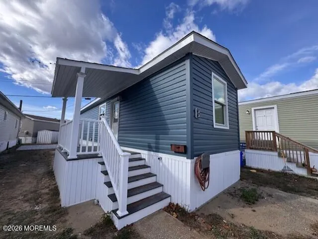 a view of a house with wooden walls stairs and a large tree