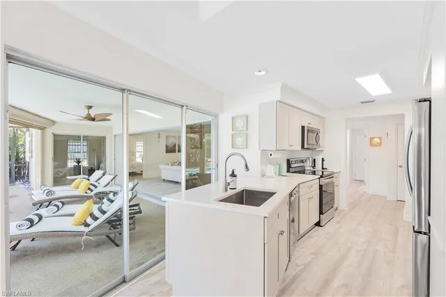 a large white kitchen with stainless steel appliances granite countertop a lot of counter top space and furniture