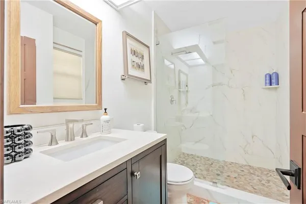 a bathroom with a sink a toilet a shower and a mirror