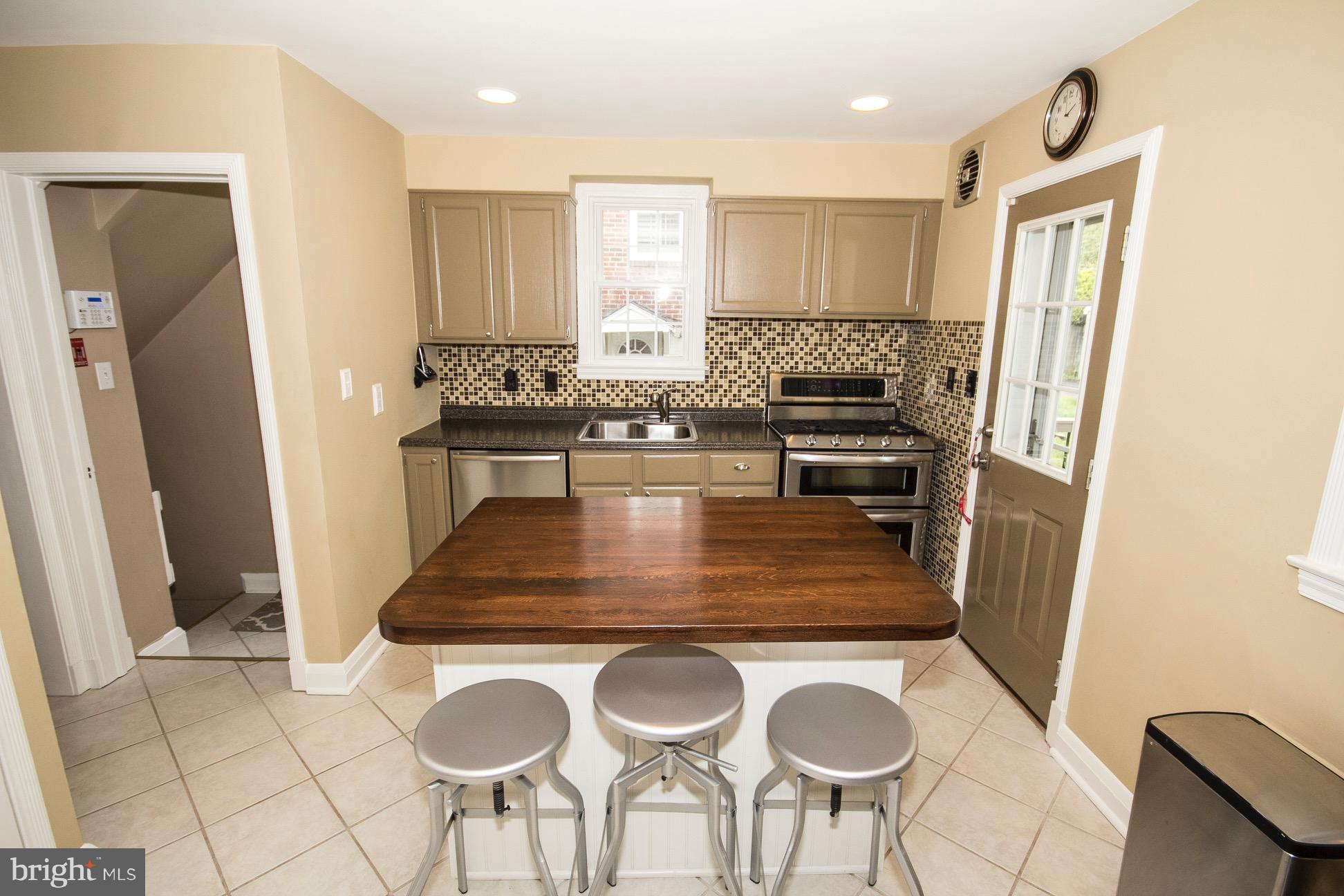 623 Overbrook Road Baltimore, MD 21212 - Photo 8 of 30 a kitchen with kitchen island a stove a refrigerator cabinets and chairs