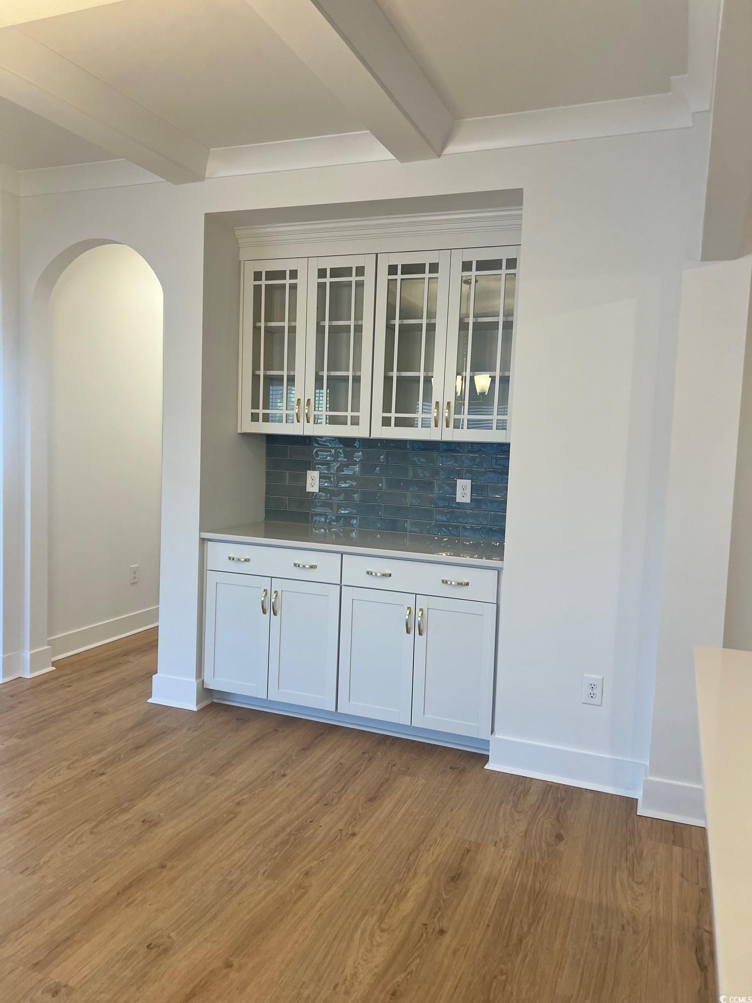 Bar with white cabinets, beam ceiling, backsplash,