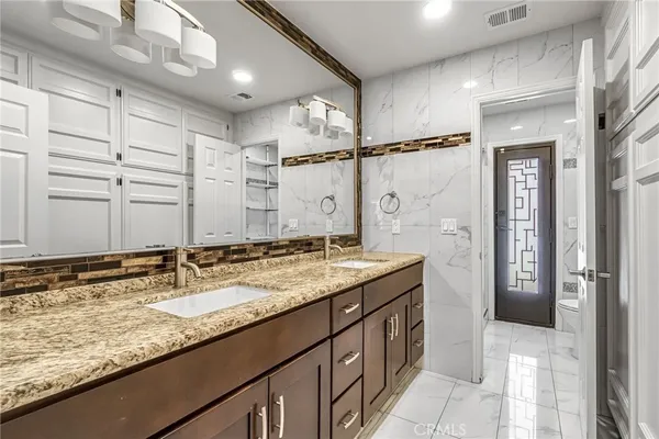 a bathroom with a granite countertop sink a mirror and a shower