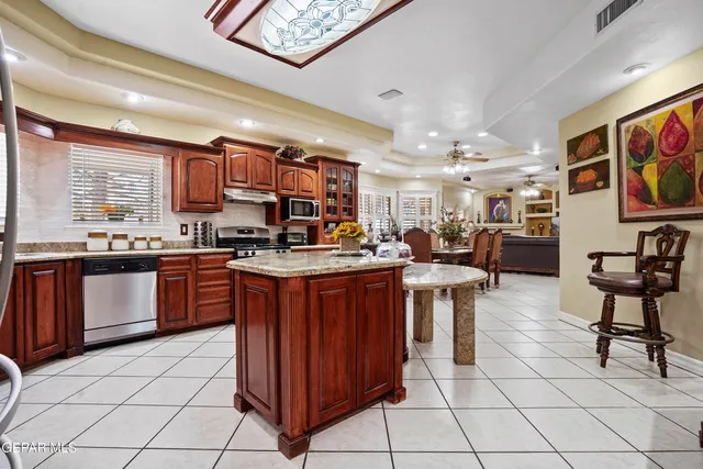 a large kitchen with a large counter top space a sink stainless steel appliances and cabinets