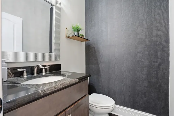 a bathroom with a granite countertop sink a toilet and mirror