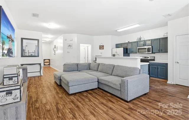 a living room with stainless steel appliances furniture and a kitchen view
