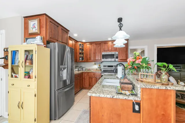 a kitchen with stainless steel appliances granite countertop a refrigerator a stove a sink a dining table and chairs with wooden floor