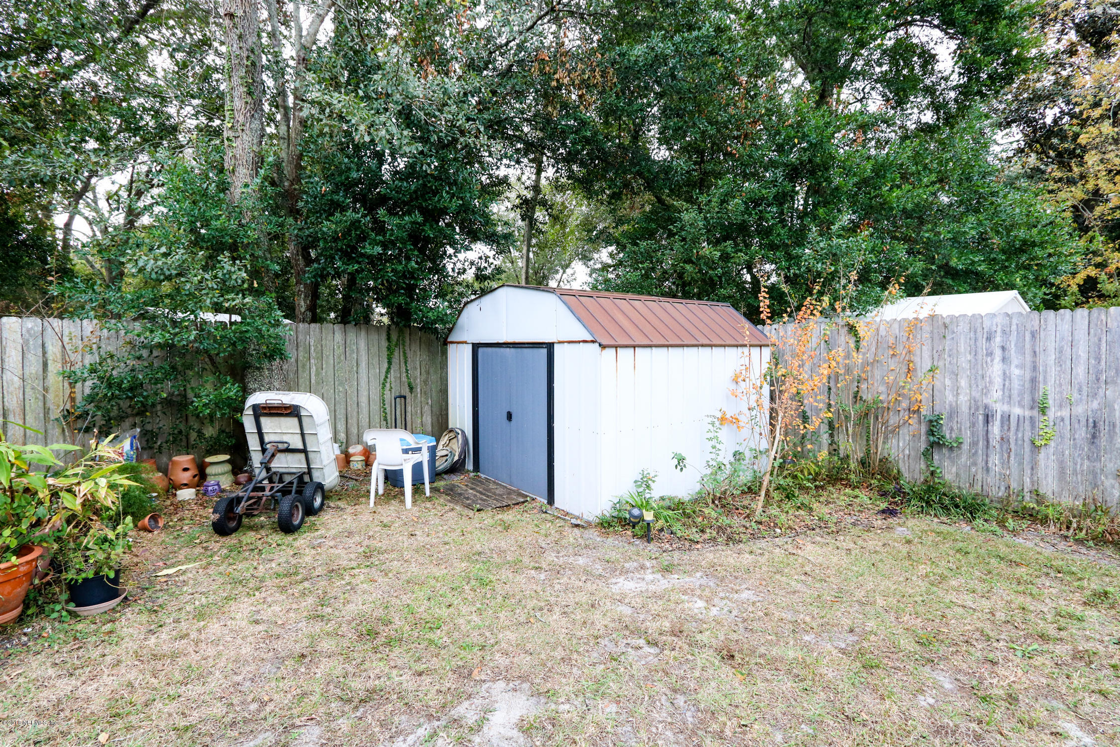 7648 Rambler Road Jacksonville, FL 32244 - Photo 27 of 29 a backyard of a house with table and chairs under an umbrella