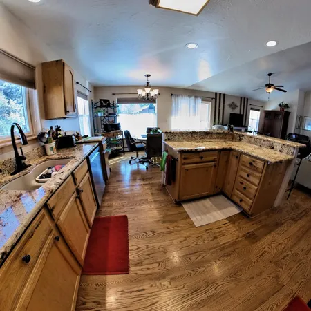 a large kitchen with kitchen island a stove a sink dishwasher and a dining table with wooden floor