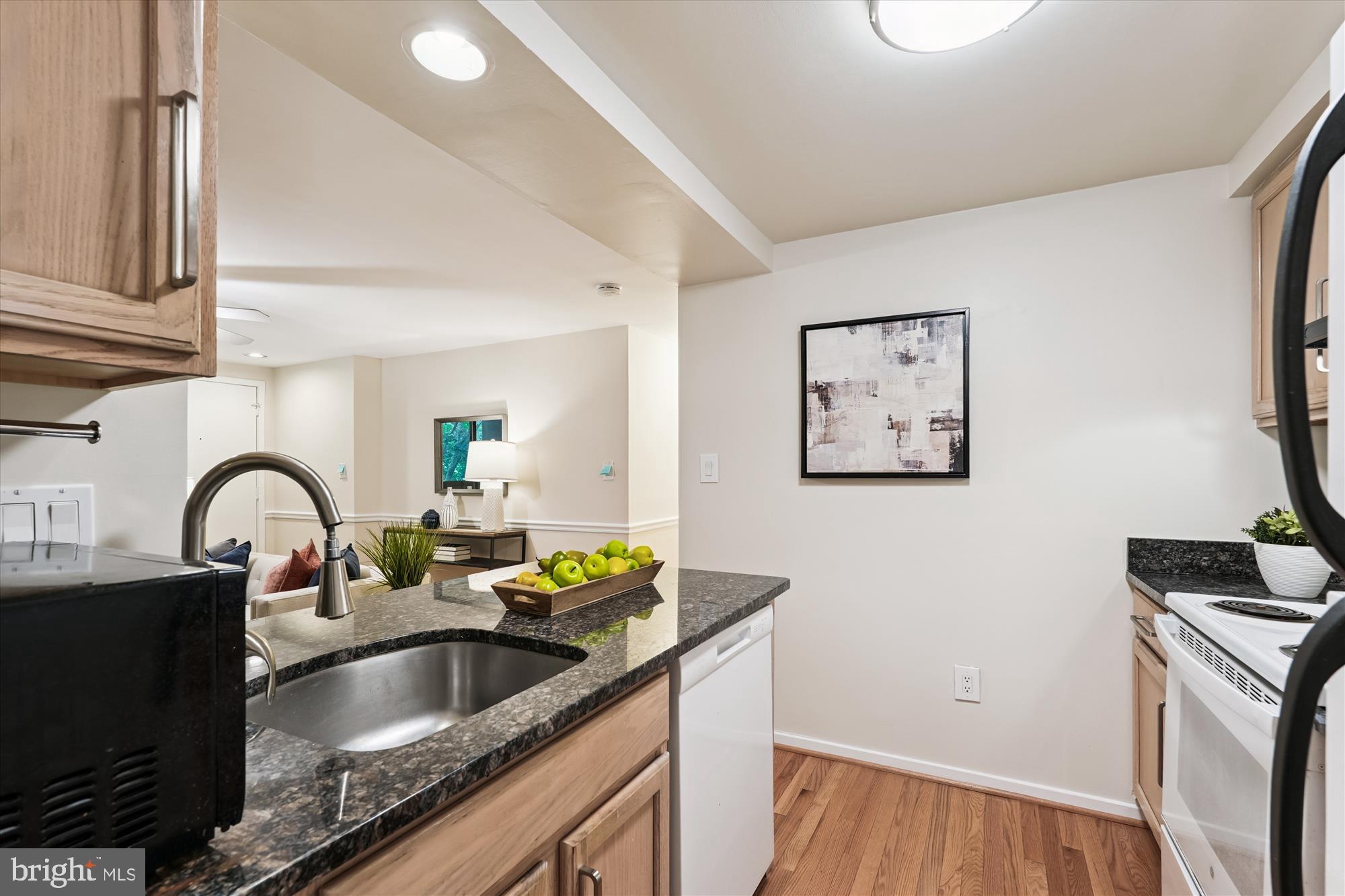 9731 Hellingly Place, Unit 37 Montgomery Village, MD 20886 - Photo 5 of 20 a kitchen with granite countertop a sink and a stove top oven with wooden floor