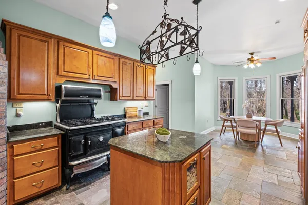 a kitchen with stainless steel appliances granite countertop a sink a stove cabinets and dining table