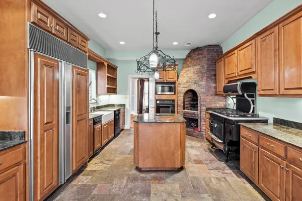 a kitchen with stainless steel appliances granite countertop a stove top oven a sink dishwasher a refrigerator and a stove