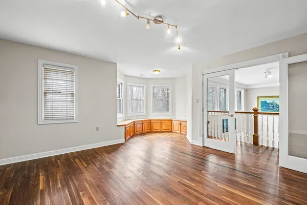 an empty room with wooden floor and windows
