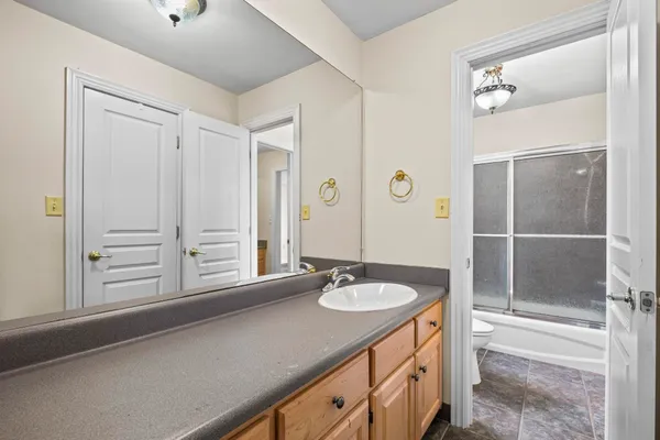 a bathroom with a granite countertop sink two mirror and a shower