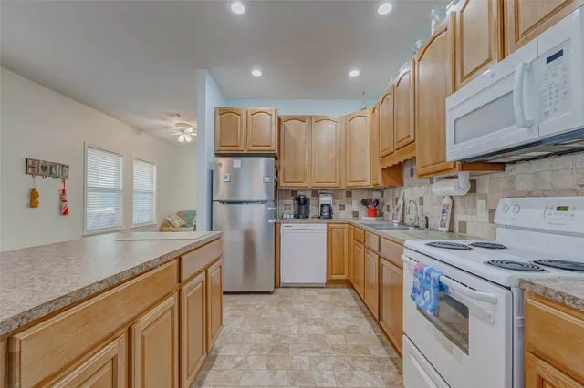 a kitchen with kitchen island granite countertop cabinets and white appliances