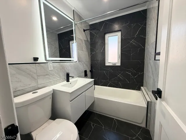 a bathroom with a sink toilet vanity and tub