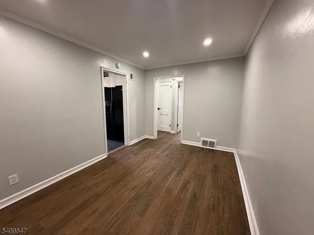 an empty room with wooden floor and a ceiling fan
