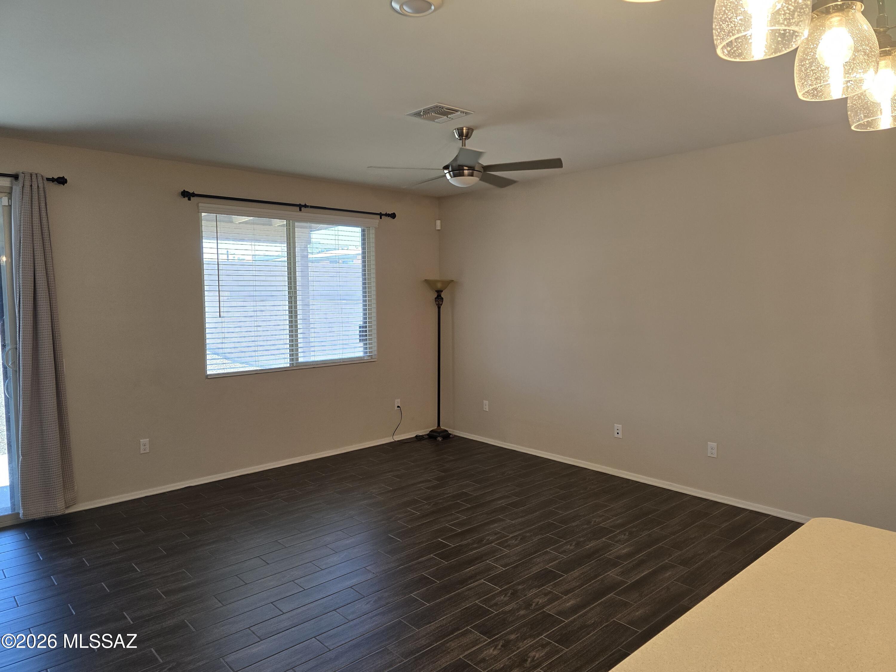 6151 South Antrim Loop Tucson, AZ 85706 - Photo 6 of 13 an empty room with wooden floor chandelier fan and windows