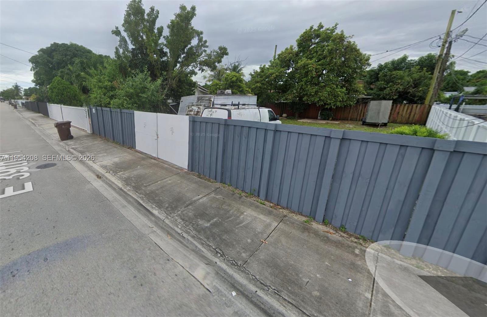 a view of a backyard with wooden fence and trees