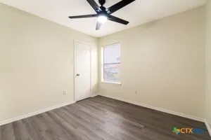an empty room with a ceiling fan and wooden floor