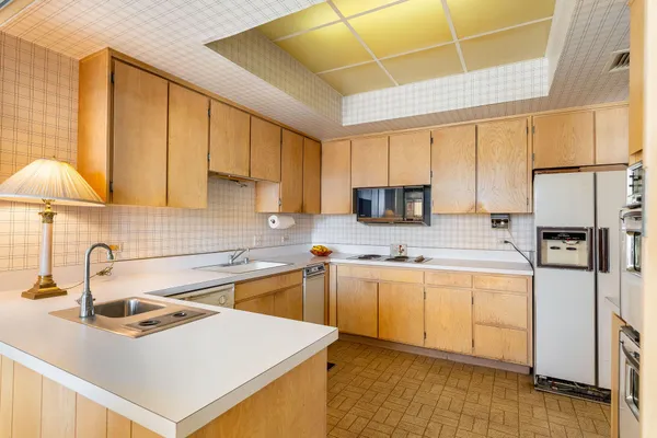 a kitchen with stainless steel appliances a sink a stove a refrigerator cabinets and a window