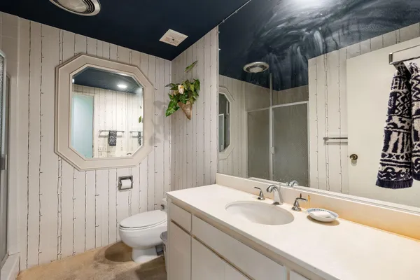 a bathroom with a granite countertop sink a toilet and shower