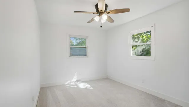 an empty room with a window and a fan