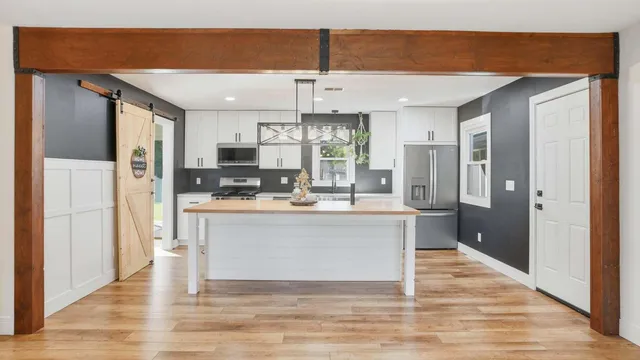 a view of kitchen with stainless steel appliances refrigerator stove microwave and cabinets