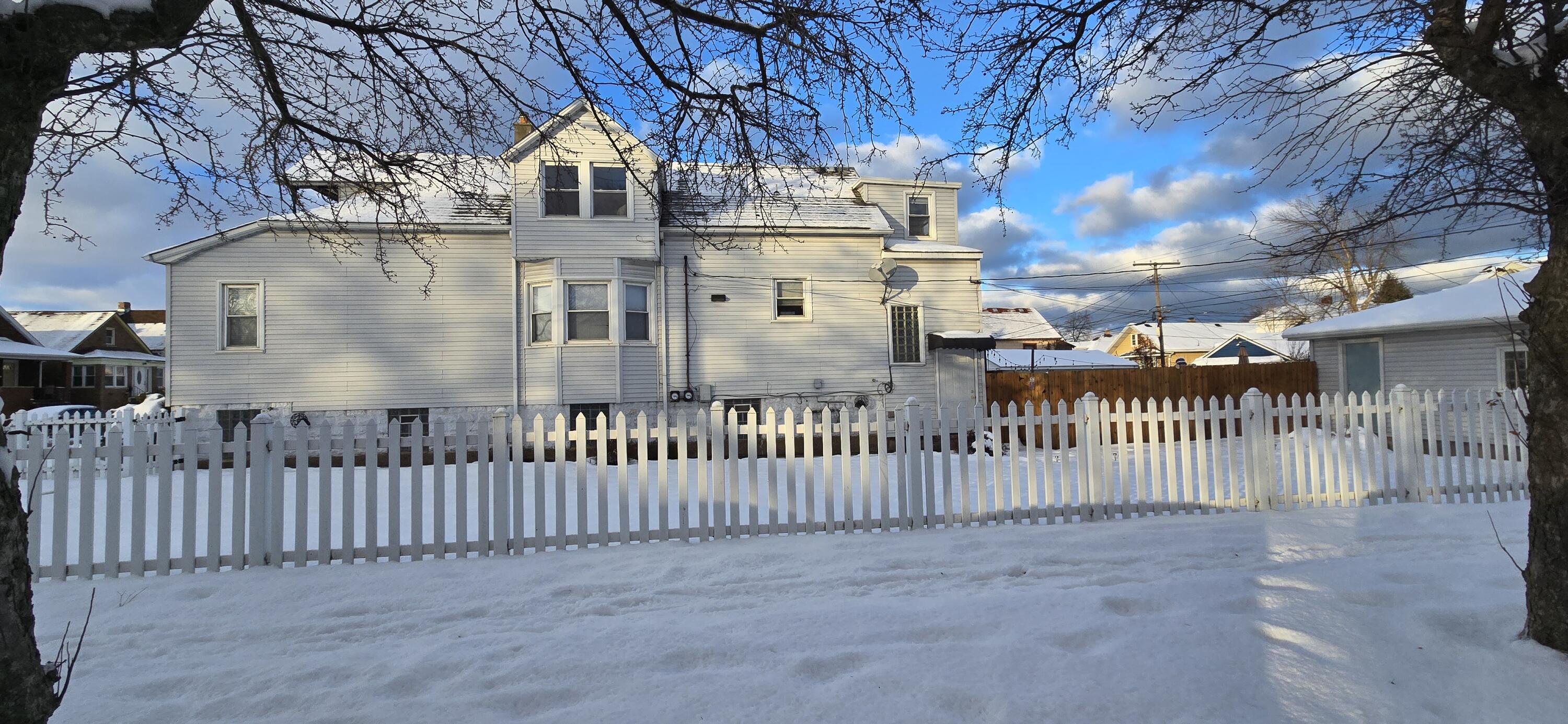 1647 Myrtle Avenue, Unit 1 Whiting, IN 46394 - Photo 20 of 20 a view of a white house with large trees and wooden fence