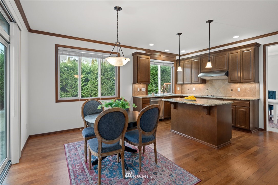 4421 220th Street Southeast Bothell, WA 98021 - Photo 13 of 39 a kitchen with stainless steel appliances granite countertop a sink a stove a refrigerator wooden floor and a dining table