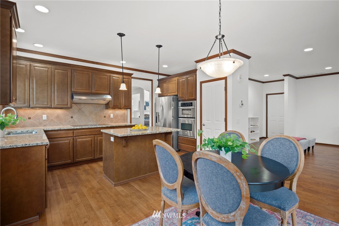 4421 220th Street Southeast Bothell, WA 98021 - Photo 14 of 39 a kitchen with granite countertop a dining table chairs stainless steel appliances and cabinets