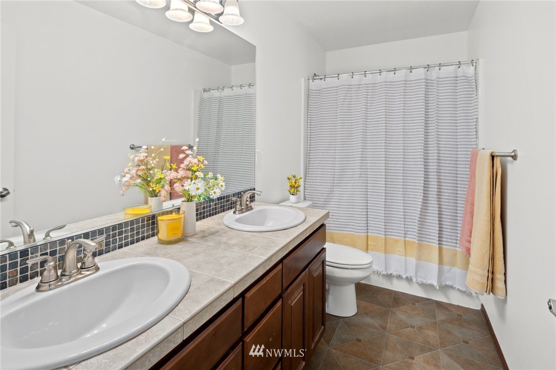 4421 220th Street Southeast Bothell, WA 98021 - Photo 31 of 39 a bathroom with a granite countertop sink a toilet a mirror and shower