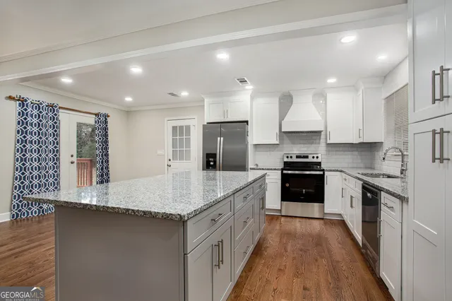 a large kitchen with stainless steel appliances granite countertop a stove refrigerator and a sink