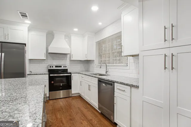 a kitchen with stainless steel appliances granite countertop a stove a sink and a refrigerator