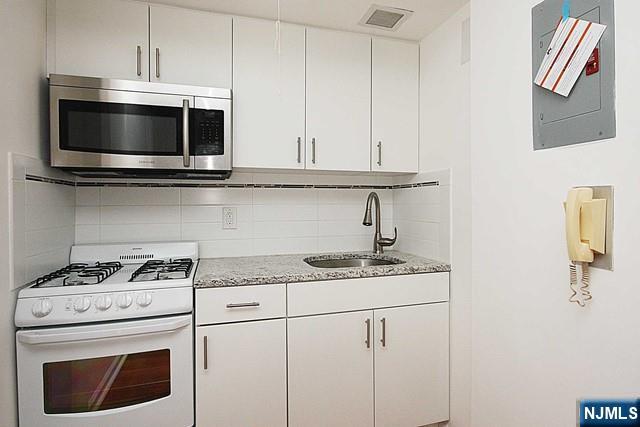 3020 Edwin Avenue, Unit 2J Fort Lee, NJ 07024 - Photo 4 of 8 a kitchen with granite countertop white cabinets and stainless steel appliances