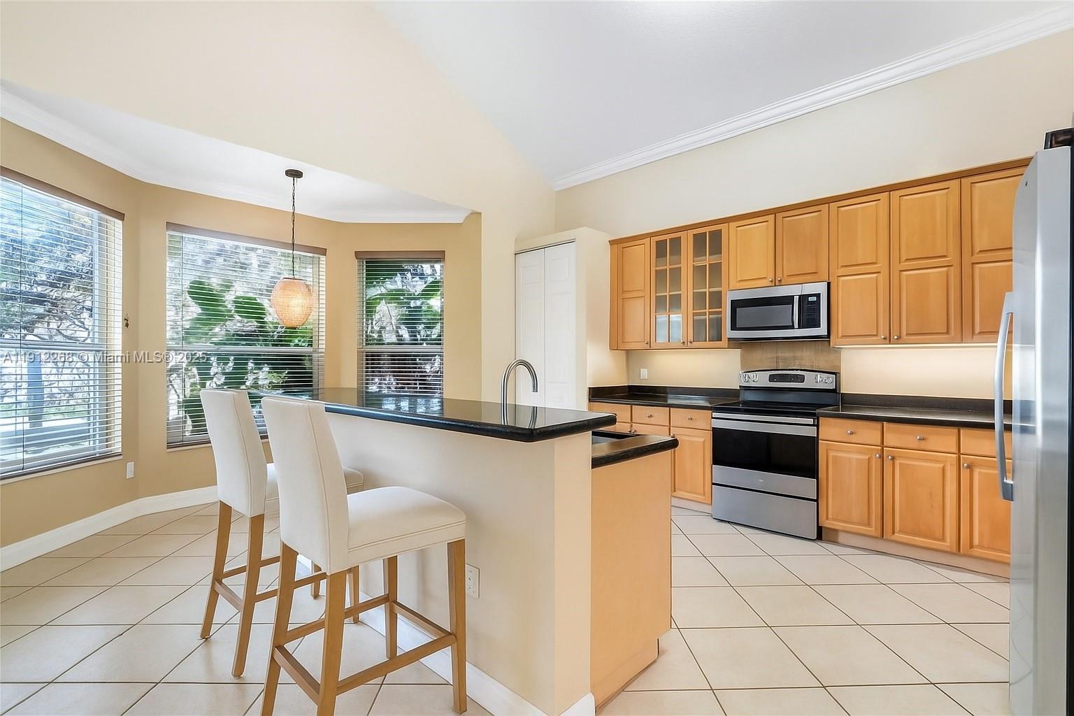 16285 Southwest 19th Street Miramar, FL 33027 - Photo 3 of 36 a kitchen with stainless steel appliances granite countertop a stove top oven a sink dishwasher a dining table and chairs with wooden floor