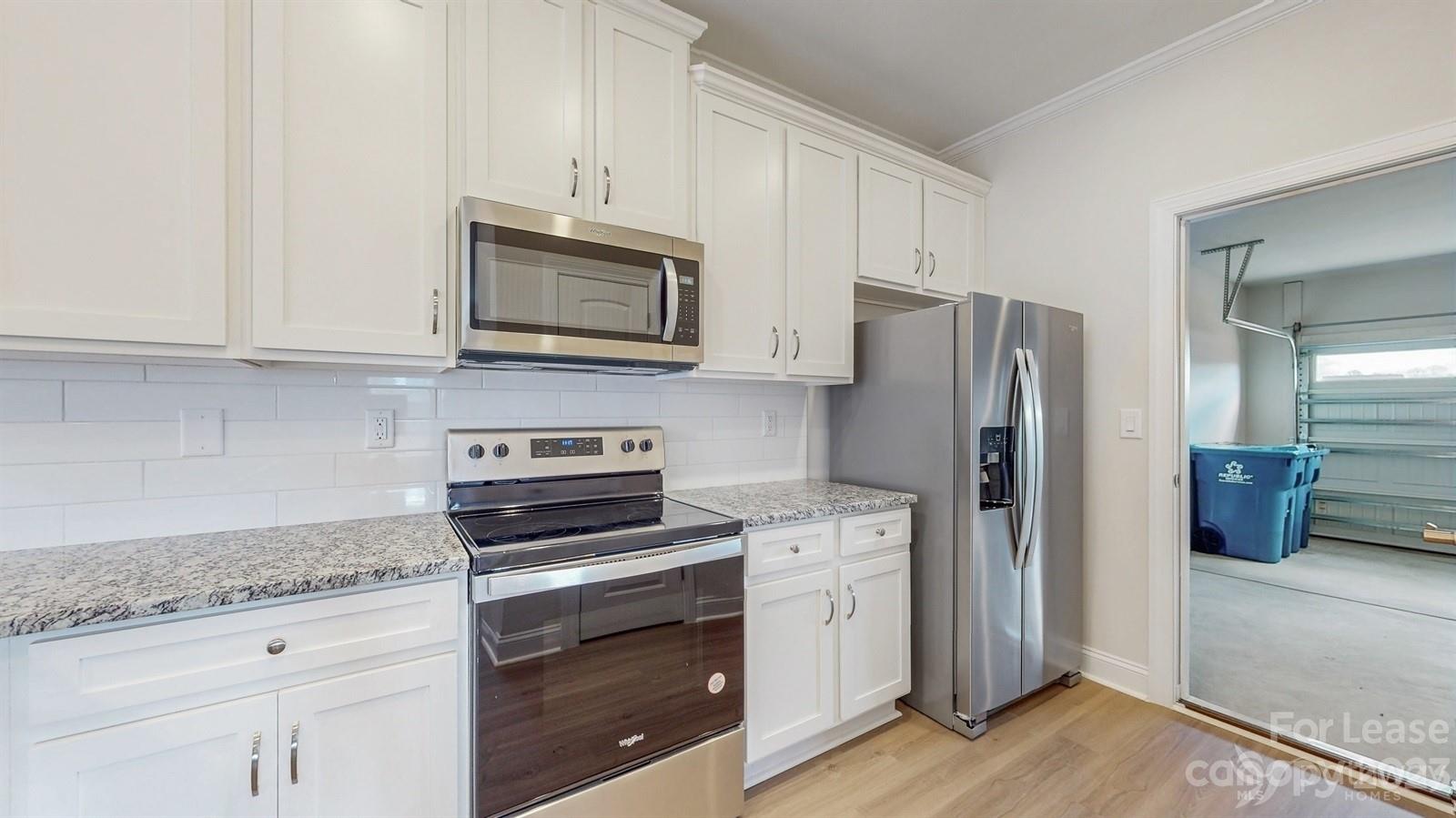 163 Brixham Loop Troutman, NC 28166 - Photo 10 of 34 a kitchen with granite countertop a refrigerator stove and cabinets