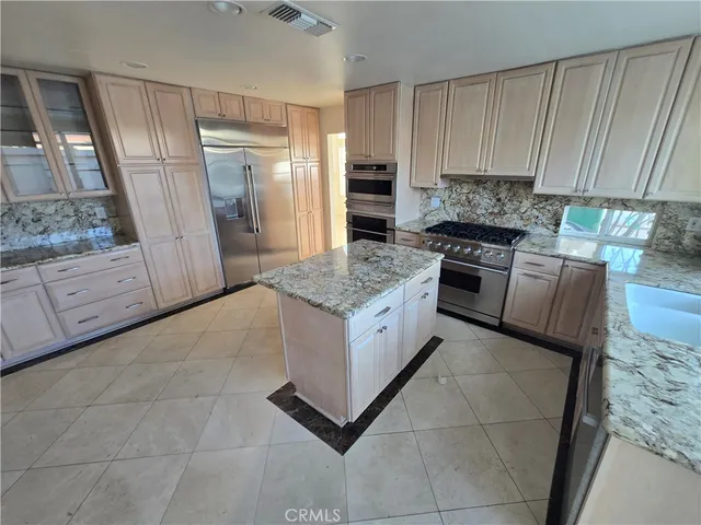 a kitchen with granite countertop a stove a sink and a refrigerator