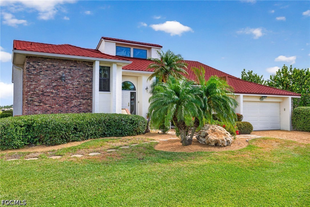 1057 Sand Castle Road Sanibel, FL 33957 - Photo 4 of 50 a front view of a house with a yard and garage